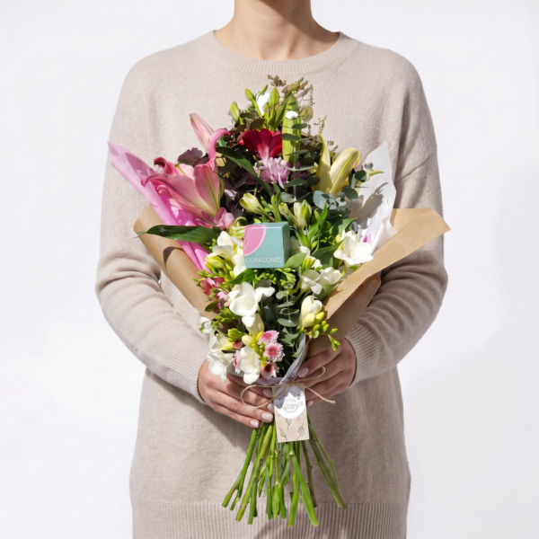 Ramo de flores naturales de estación con lilium y follaje, sostenido entre las manos