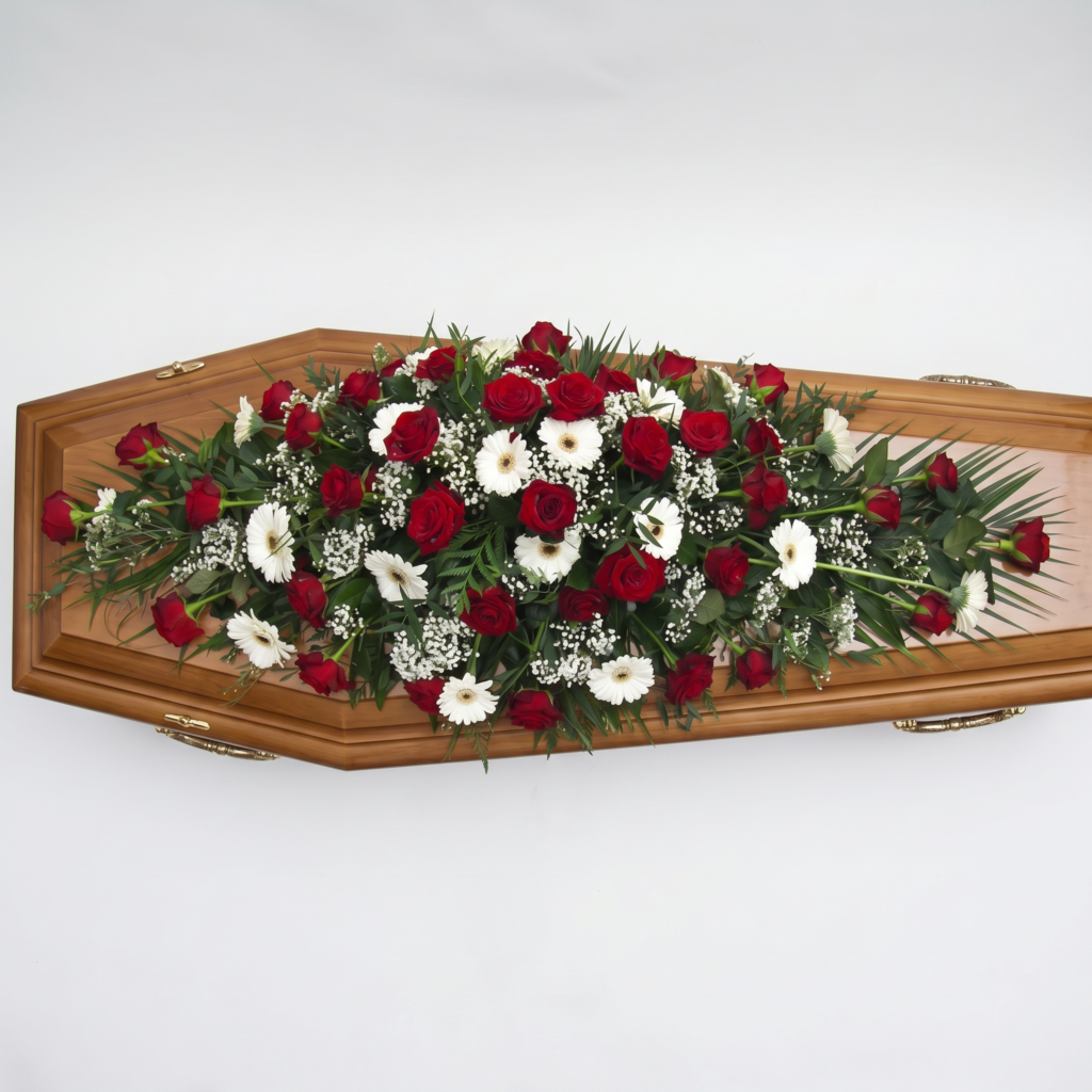 Cubre ataúd de rosas rojas y flores blancas colocado sobre la tapa de un ataúd de madera
